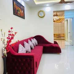 A plush, tufted red sectional sofa adds a pop of color and luxury to this living room. I focus on selecting furniture that is both stylish and comfortable for the whole family to enjoy.
