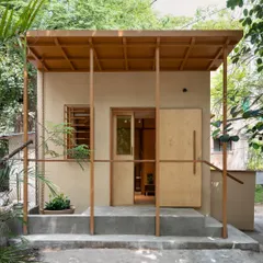 The exterior of the clinic is a simple, modest structure surrounded by greenery, designed to feel more like a garden pavilion than a medical facility.