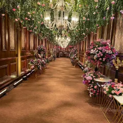 Imagine walking through a celestial garden. For this regal indoor wedding, I designed a breathtaking floral passage with a ceiling of cascading greenery and fresh pink blooms, lit by elegant crystal chandeliers to create a truly romantic and immersive entrance.
