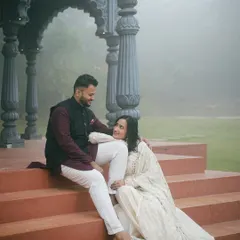 A candid moment captured on the steps of the Indian palatial set. The terracotta colored stairs contrast beautifully with the grey stone pillars and the soft, foggy backdrop.