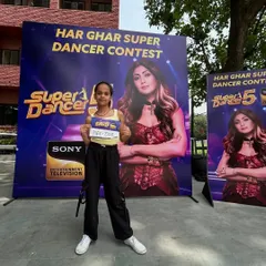 One of our talented students proudly displaying her audition number at the 'Har Ghar Super Dancer Contest'. We prepare each dancer with custom choreography to help them shine.
