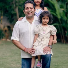 A proud father with his two daughters. This outdoor family portrait captures the warmth and protective love that defines their relationship.
