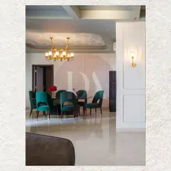 A closer look at the dining area where deep emerald chairs gather around the table. The design features a textured ceiling detail and a modern brass chandelier, creating a space that feels both luxurious and ready for conversation.