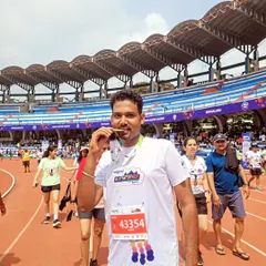 Biting the medal is a classic runner’s pose for a reason. It’s a celebration of months of hard work, early morning runs, and the support of the community, all culminating in this moment at the Kanteerava Stadium.
