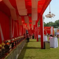 This is an example of a long tent I set up specifically for a food service area. The structure provides shelter and is decorated with fabric and lighting to maintain the event's overall aesthetic.