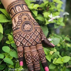 A single hand featuring the lotus mandala design, set against a natural green background.