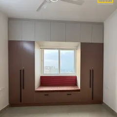 Another take on our popular window seat design. Here, we used a combination of brown and grey laminates for the wardrobes, creating a warm and inviting nook with a pop of color from the cushion.