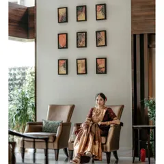 An elegant, full-length bridal portrait, with the bride seated in a modern armchair, looking poised and beautiful.