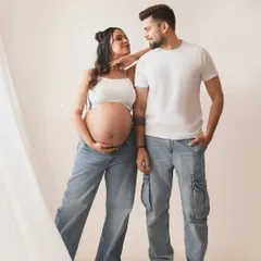 A cool and casual couple portrait. Dressed in jeans and white tops, their relaxed pose and loving gaze make for a stylish and modern maternity photo.