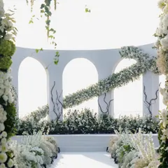 The interplay of light and shadow on the white floral structures. The design was carefully planned to look beautiful in the bright sunlight, with hanging greenery and layered flowers creating depth and texture.