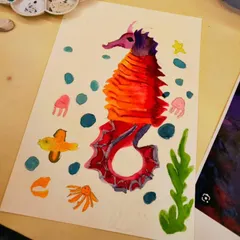 A close-up of a finished watercolor seahorse. The students learned blending and layering techniques to create the vibrant red and orange scales.