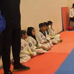 Young students sitting patiently, learning the importance of discipline and respect during a competition.