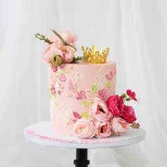A truly beautiful birthday cake for a royal celebration. This pink cake features a delicate stencil pattern and is adorned with fresh peonies and a miniature gold crown.