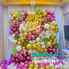 Let's make your birthday pop with a vibrant balloon wall. This full-wall installation uses a mix of metallic pink, gold, and white balloons, accented with tropical leaves and a custom "Happy Birthday" neon sign, creating a perfect backdrop for photos.