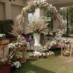 A trendy circular arch made of pampas grass and pastel flowers, serving as a beautiful photo backdrop. The custom '#SaCha' lettering adds a personal touch for the couple.