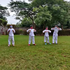 Thumbs up for outdoor karate. This group is feeling proud and energized after a session in the park, showing their enthusiasm for learning martial arts together.