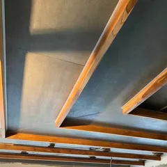 A detail of the ceiling structure in the Lucknow penthouse during construction. The image shows the interplay between the exposed concrete slab and the custom wooden beams that define the geometry of the space.