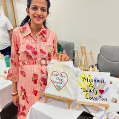 A guest at a baby shower proudly displays the personalized baby t-shirt and canvas she painted for the parents-to-be.