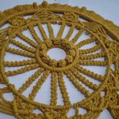 An overhead detail shot of the macrame mandala, highlighting the radial symmetry and the texture created by hundreds of individual knots.