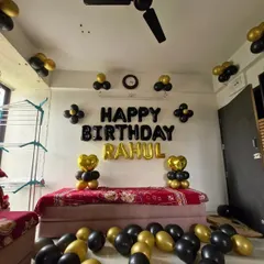A full room view of the birthday decoration, with black and gold balloons scattered on the floor and ceiling.