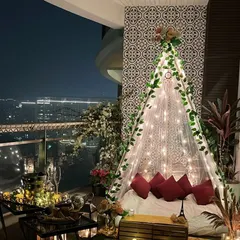 We create magical moments with romantic proposal decorations. This intimate balcony setup features a beautiful teepee canopy illuminated with fairy lights against the city skyline, setting the perfect mood for a 'yes'.