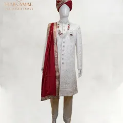 The quintessential royal groom's attire. This is my classic all-white, intricately embroidered sherwani, perfectly complemented by a rich maroon stole and a matching turban for a look of timeless elegance on your wedding day.