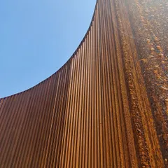 The rich, rusted texture of the Corten steel provides a warm, earthy contrast to the blue sky.