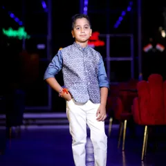 A full-length portrait of the birthday boy in his smart ethnic wear, confidently posing for the camera. The dark, atmospheric background with neon lights makes the subject stand out.