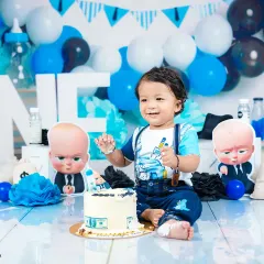 A fun and memorable "Boss Baby" themed cake smash for a first birthday. This shot captures the pure, messy joy of a baby enjoying his first taste of cake in a creative, fully-styled setup.
