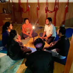 A mixed group of students gathered for Tratak meditation. The candle flame provides a single point of focus, helping to improve concentration and bring a sense of calm.