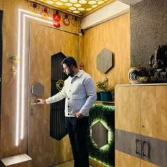 A stunning entrance at a Prateek Laurel project. The design features a wooden door with vertical light strips, a hexagonal-themed ceiling, and a matching shoe cabinet with a green moss accent.
