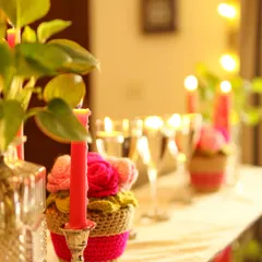 The soft focus on this shot captures the dreamy, warm atmosphere created by the candles and crochet flowers.