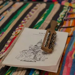 A kirtan booklet and a kartal, a traditional percussion instrument, rest on a colorful mat. Chanting and devotional music are an important part of our retreats, helping to open the heart and quiet the mind.