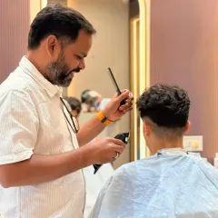 The finishing touches are key. Here, our stylist is perfecting the haircut with a comb and clipper, ensuring every detail is just right.