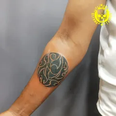 An abstract circular tattoo on the elbow. This design uses negative space to create a flowing, organic pattern that is both modern and unique.