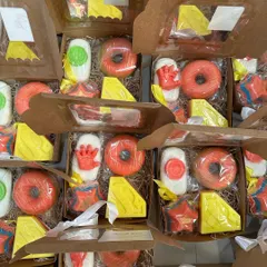 A collection of superhero-themed return favor boxes ready for a 5-year-old's birthday party. Each box is filled with a variety of hero-inspired soaps like the Iron Man hand, Superman logo, and a donut soap.