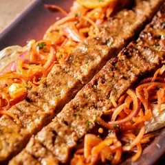 Another angle of the Murg Adana Seekh, highlighting the beautiful char marks and the vibrant colors of the accompanying salad.