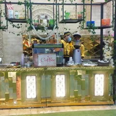 For a more elegant theme, I designed this coffee station with a gold mirrored counter and a black metal frame adorned with ivy. It includes a professional coffee grinder and espresso machine for authentic café service.