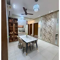 This dining area at Ivy County is both luxurious and inviting. A marble-top table is surrounded by plush beige chairs, set against a backdrop of textured wallpaper and mirrored panels.