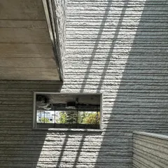 Sunlight grazes the textured stone facade of a building under construction, creating strong diagonal shadows. We design our building skins to actively engage with light, creating surfaces that change their appearance throughout the day.