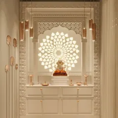 This all-white mandir design achieves a divine glow with a large, backlit floral mandala behind the Ganesha idol. The intricate jali arch and modern pendant lights add layers of sophistication and brightness.