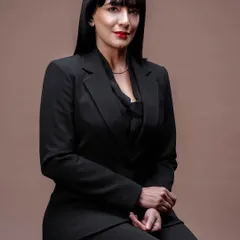 Adding a touch of colour and a bold red lip transforms the look. This seated portrait feels confident and approachable, showing versatility within a single professional photoshoot.