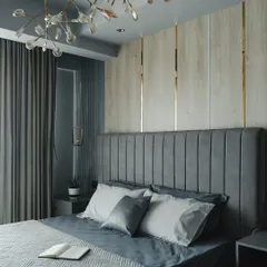 This bedroom is all about serene elegance. I designed a vertically channeled grey headboard and paired it with wood-paneled walls featuring delicate gold inlays. The unique branch-like chandelier adds a touch of organic artistry to the space.