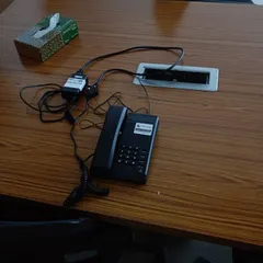 A desk setup showing an intercom phone connected through a port on the table. We manage all the wiring to keep your workspace clean and organized.