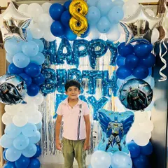 Here's a Batman-themed birthday we designed for an 8th birthday. The decor uses a blue, light blue, and white color scheme with a silver foil curtain, Batman-themed foil balloons, and a large number '8' balloon.