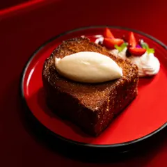 A slice of French toast with cream and strawberries on a striking red plate. The color contrast makes this image incredibly bold and eye-catching.