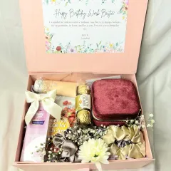 A "Happy Birthday Work Bestie" hamper. This curated box includes a velvet jewelry case, Ferrero Rocher, body oil, and scrunchies, all tied together with a beautiful ribbon.