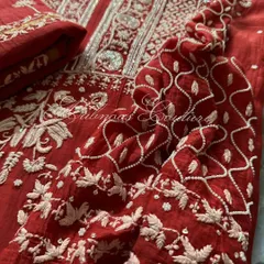 This image focuses on the sleeve and side panel of the red Anarkali, showing the continuity of the intricate embroidery and the quality of the Mul fabric.