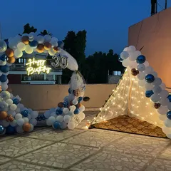 A slightly different angle of the 30th birthday terrace setup, showing the full arrangement of the balloon arch and the inviting fairy light tent.