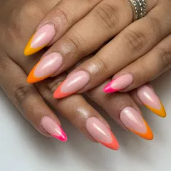 I love a modern twist on a classic. This sunkissed look features sharp, stiletto-shaped nails with a vibrant neon French tip gradient, blending from hot pink to sunny orange and yellow.
